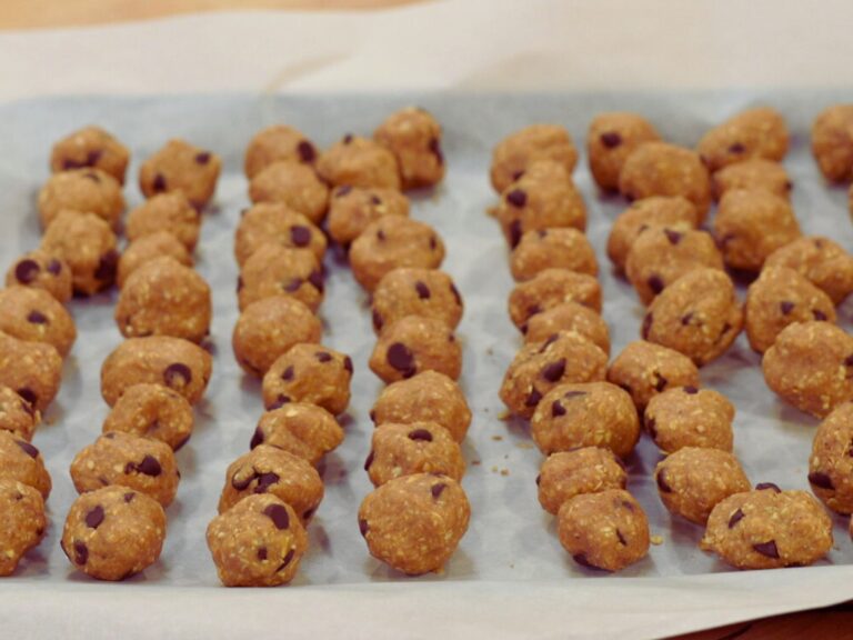 about six lines of peanut butter balls on parchment paper